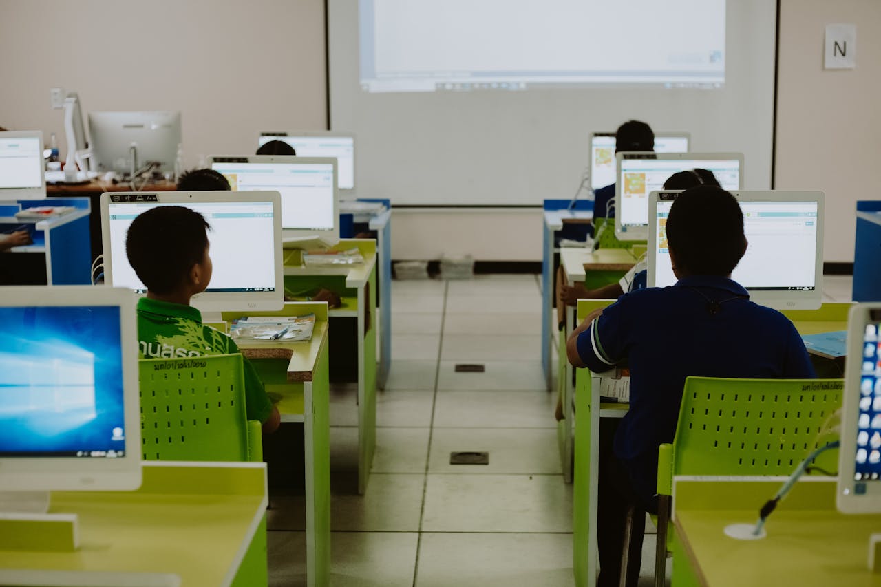services-01 Children focus on computers in a modern classroom setting.
